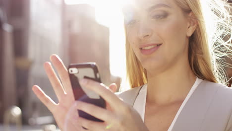 Beautiful-blonde-woman-using-smartphone-solar-flare-sunlight-energy-concept