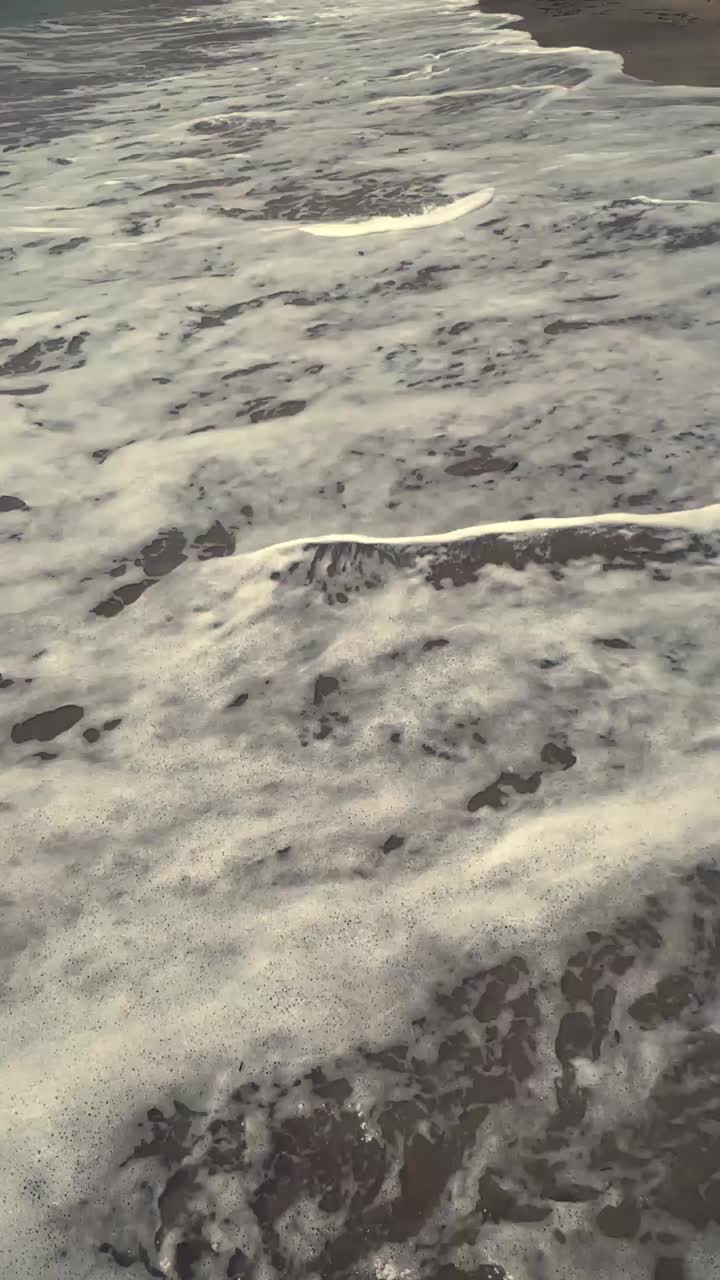 Ocean Waves Washing Ashore on a Sandy Beach with White Foam