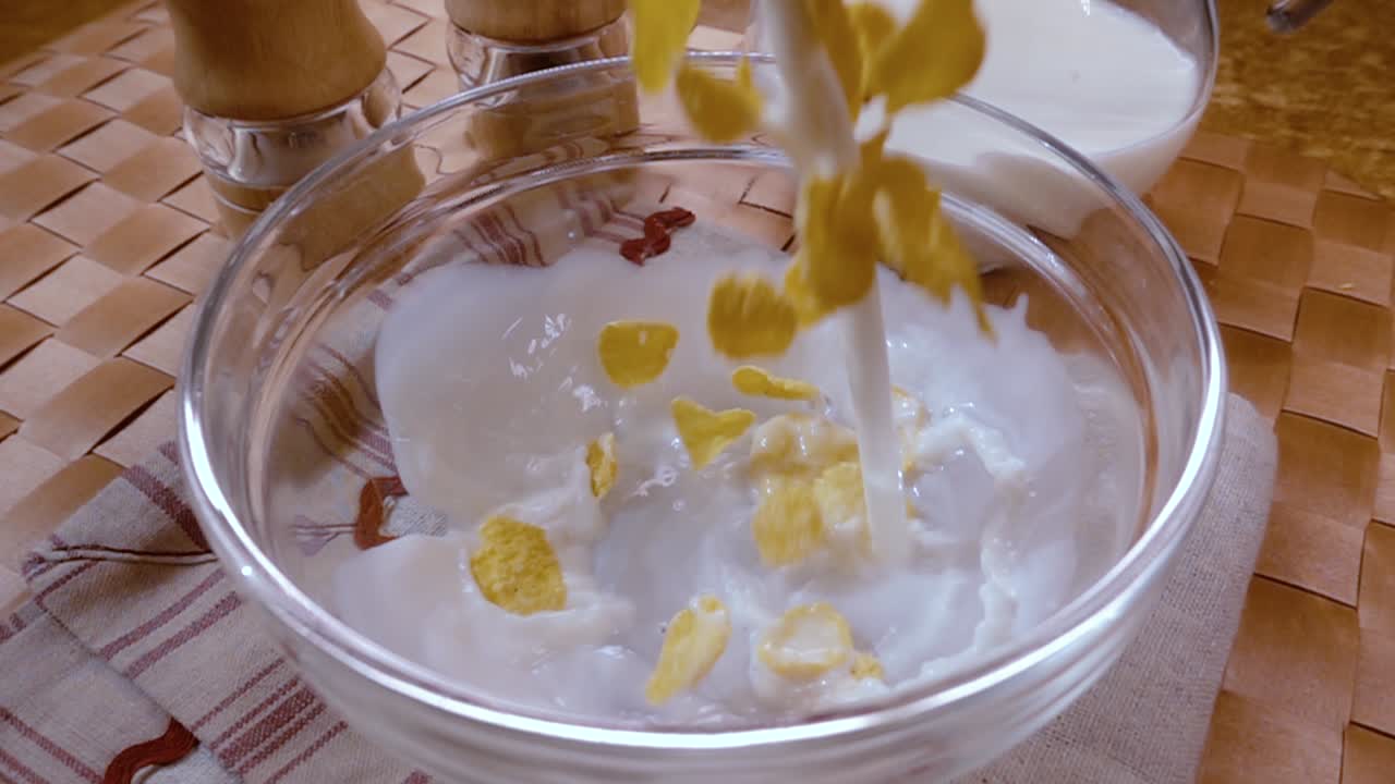 Fiocchi di mais gialli croccanti nella ciotola per una deliziosa colazione mattutina con latte. Slow motion con ripresa rotatoria.