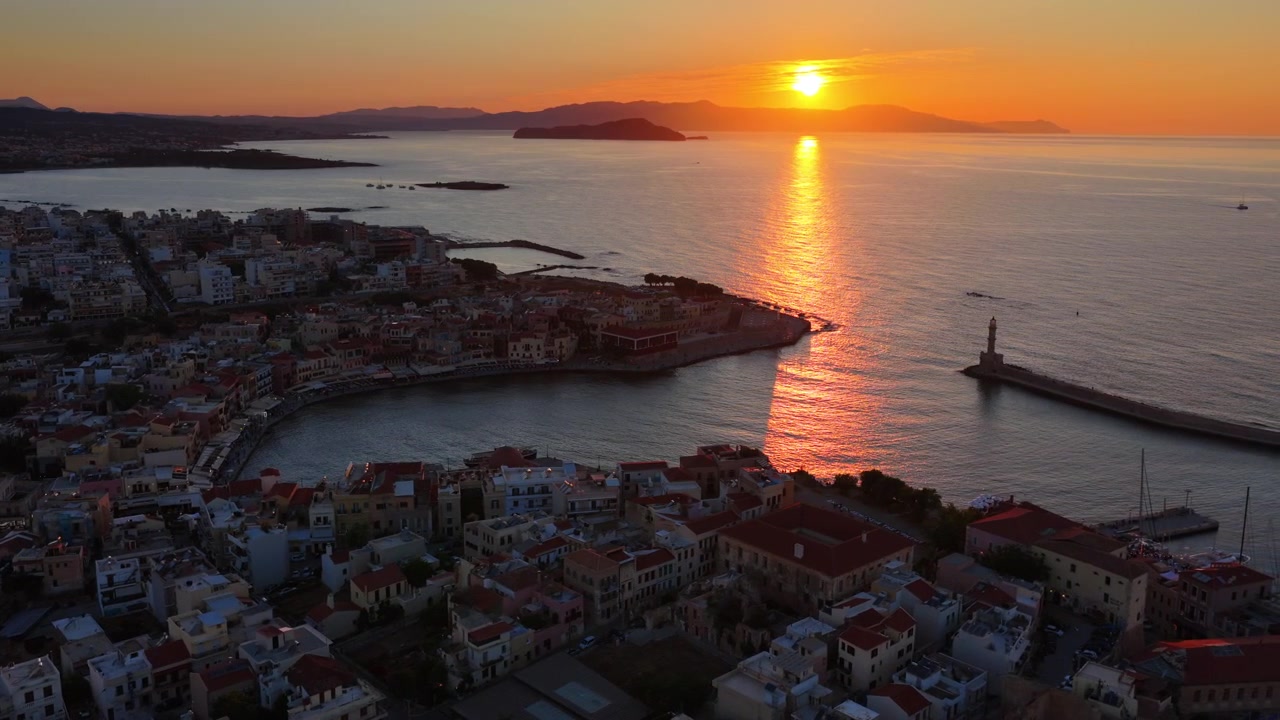 Vista aerea con drone del centro storico e del faro del porto veneziano al tramonto, con il sole che tramonta sul mare, Chania, Grecia