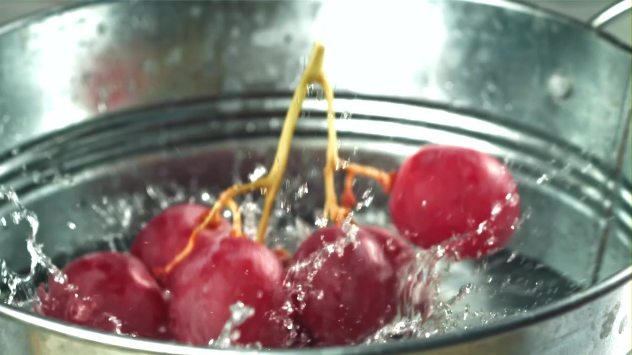 Uva rossa fresca che si tuffa nell'acqua in un secchio di metallo.