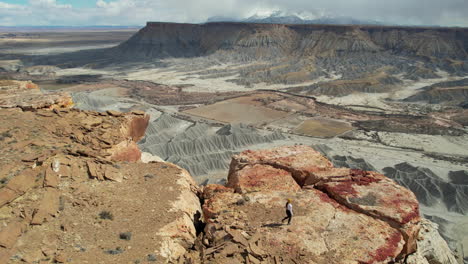 Drohnenaufnahme-Einer-Frau,-Die-Zum-Rand-Einer-Mesa-Klippe-über-Einem-Tiefen,-Trockenen-Canyon-In-Der-Wüste-Von-Utah,-USA,-Läuft