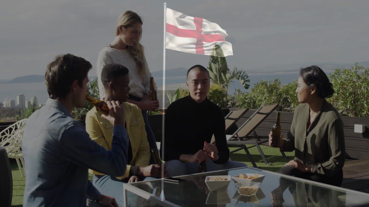 Friends on rooftop with England flag, drinking and snacking, celebrating together