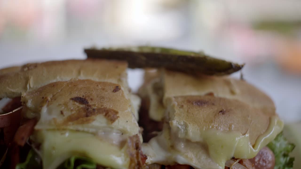 Zoom out shot revealing a grilled street sandwich cut in half, filled with ham, melted cheese and fresh lettuce