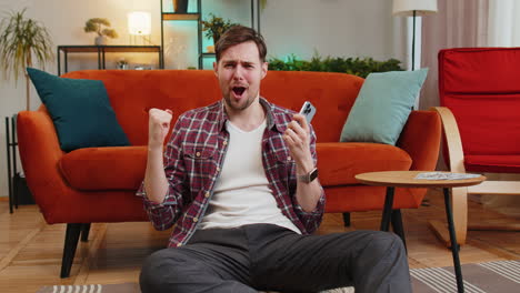 man smiling and using his phone in a living room