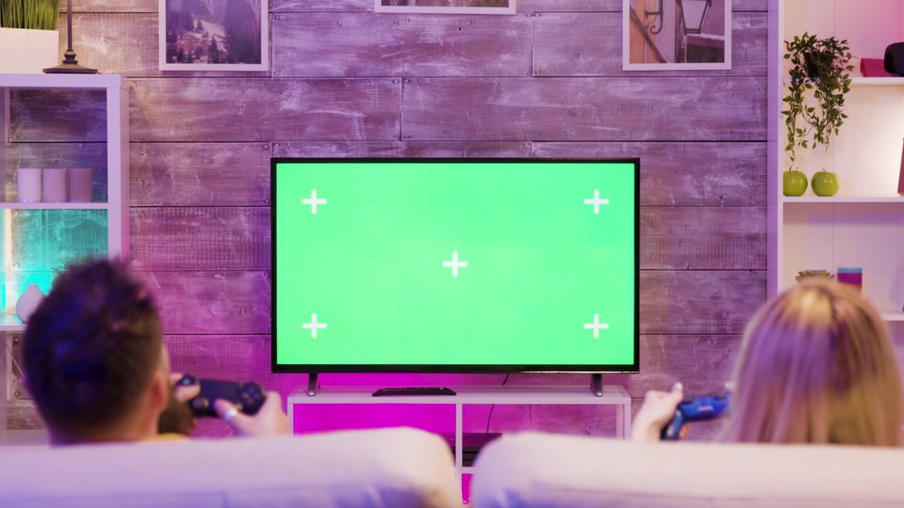Brother and sister relax with console play beside a green screen