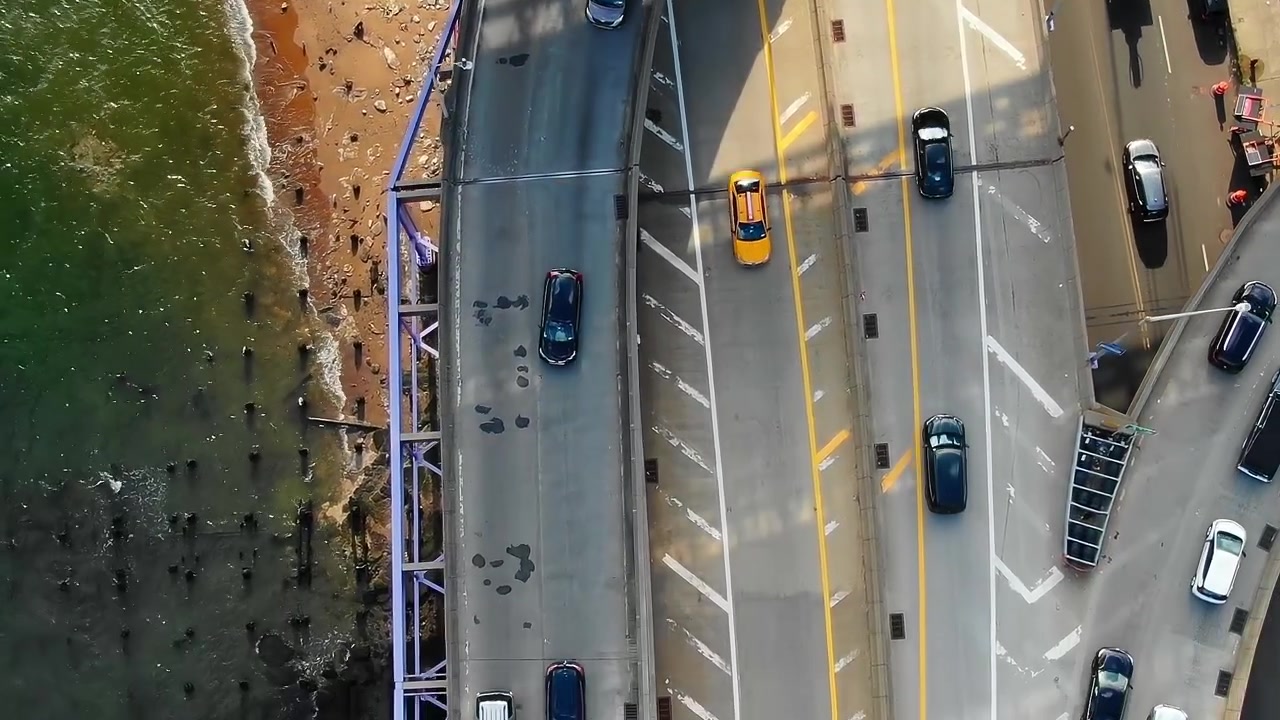 Trafik bevæger sig langs en travl gade i New York City om dagen.