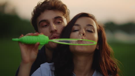 una chica encantadora y un chico lanzando burbujas en el prado. una pareja divirtiéndose en el campo