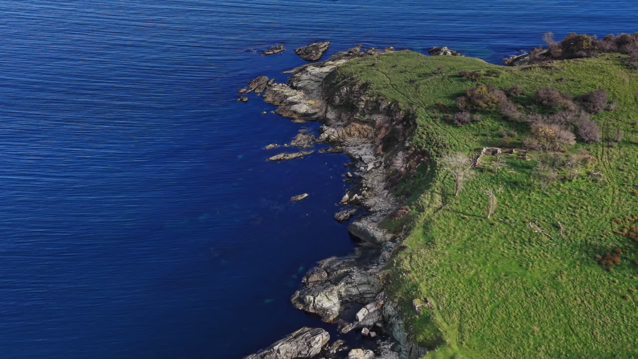 Coastal cliffs with rocky shoreline and vibrant blue waters at midday