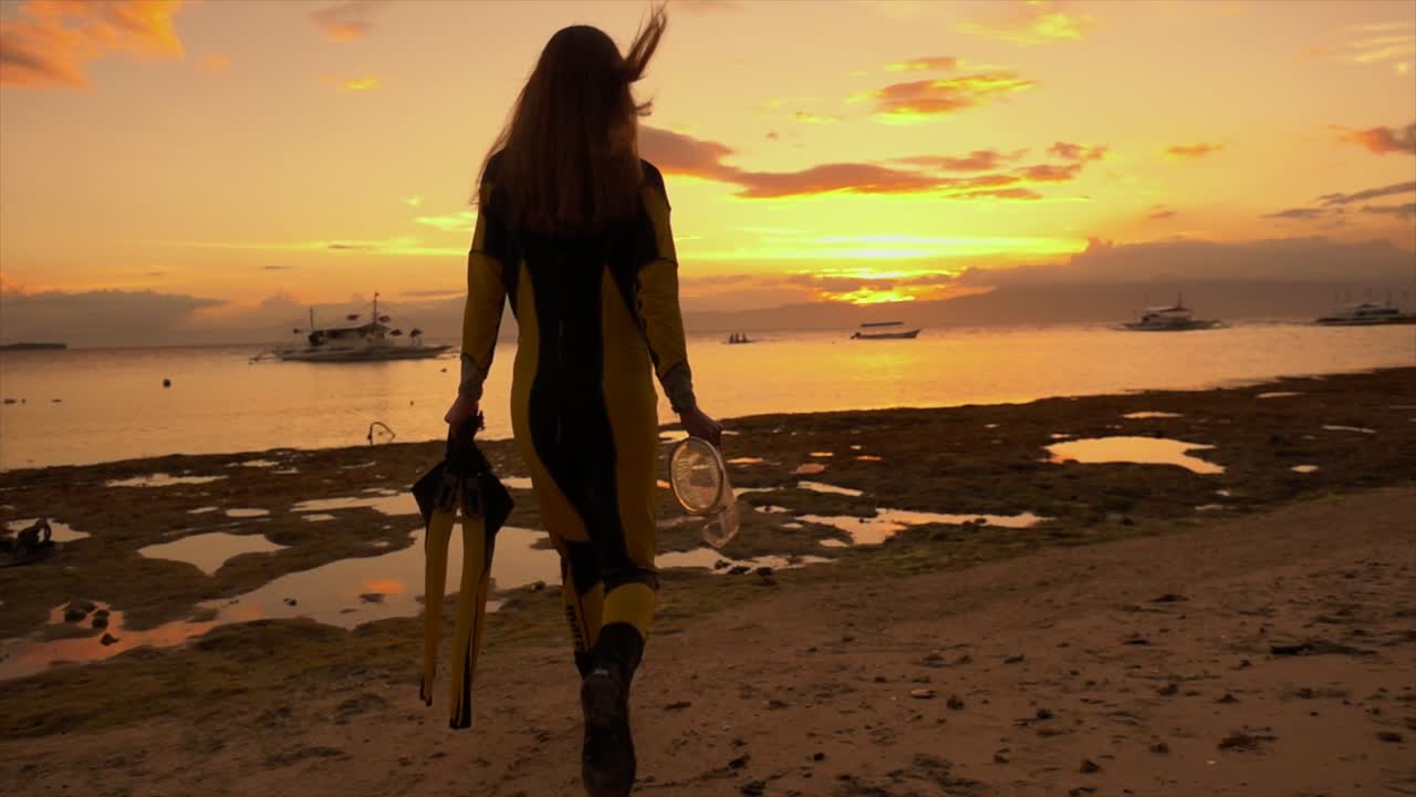Donna con attrezzatura da snorkeling che cammina nell'oceano al tramonto