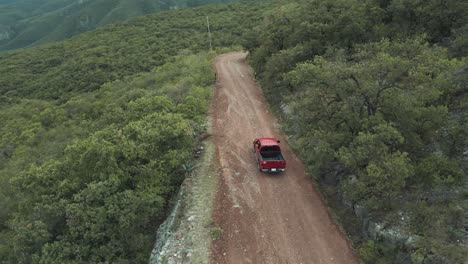 a red pickup truck drives down a dirt