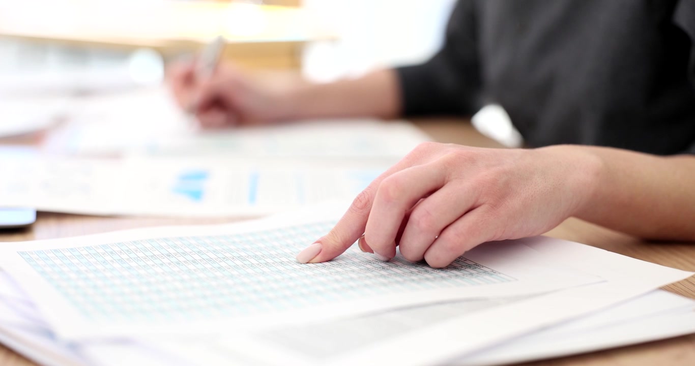 Woman accountant checks financial data working with paper tables