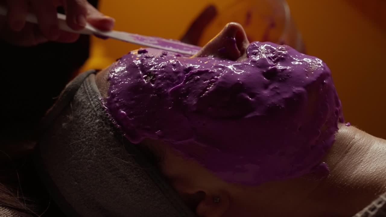 Donna sottoposta a trattamento con maschera viso viola in una spa