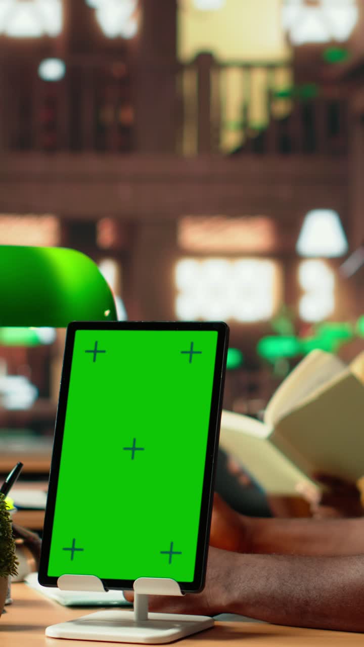 Display verticale di tablet con schermo verde in una biblioteca universitaria