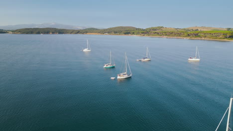 Yachts-docked-offshore-Tuscan-beach-Italy,-sunny-luxury-morning