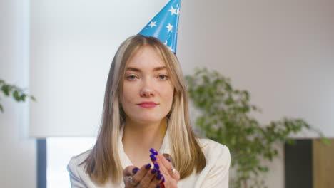 ritratto di una ragazza felice che soffia coriandoli alla festa in ufficio