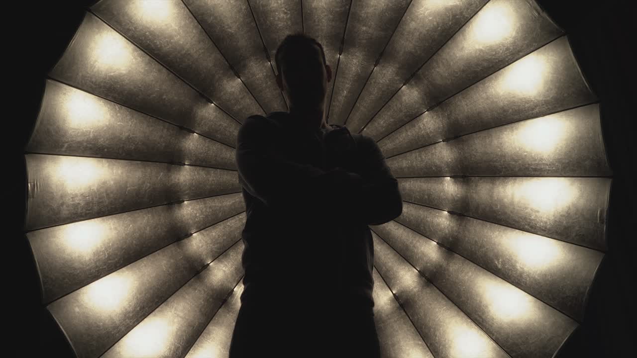 una persona ante el gran paraguas de foco con los brazos cruzados