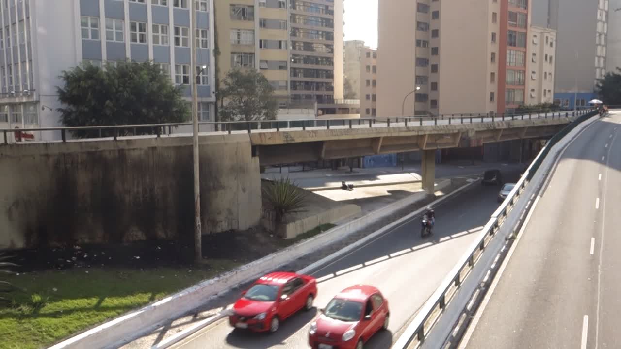 traffic on a large avenue that crosses the city center, among dozens of buildings. High angle handheld shot