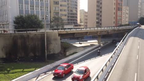traffic on a large avenue that crosses the city center, among dozens of buildings. high angle handheld shot