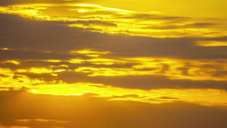 Puesta-De-Sol-De-Cielo-Dorado-Entre-Nubes-En-Movimiento,-Lapso-De-Tiempo-Relajante-Transición-Esperanzadora