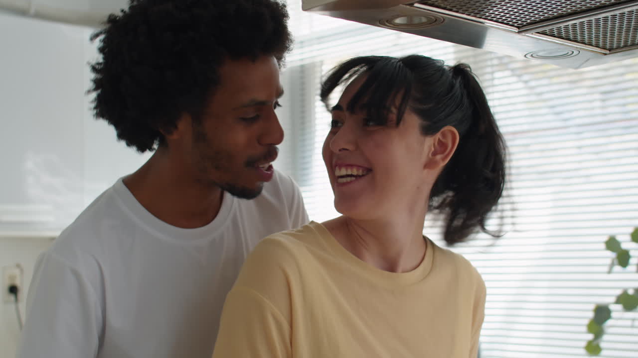 Jovem casal cozinhando ovos fritos e se beijando