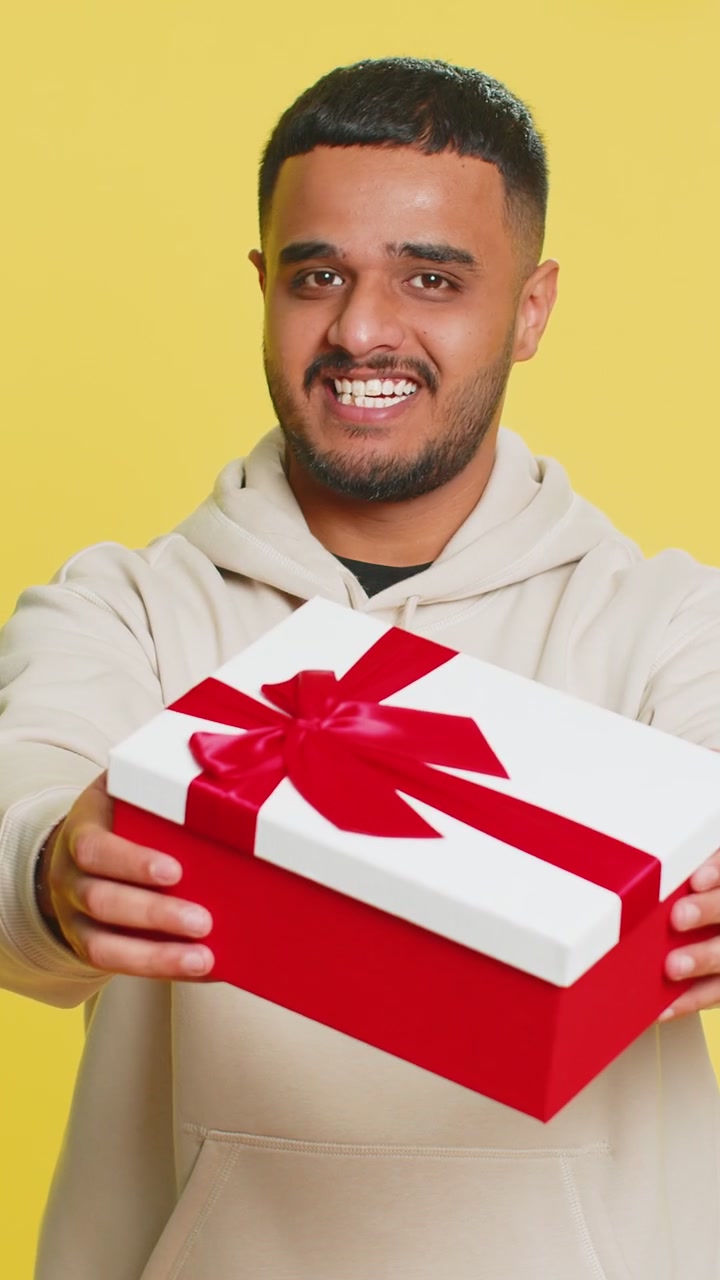 Uomo sorridente che presenta un regalo di compleanno. La scatola di regali allunga le mani. Promozione, sconto.