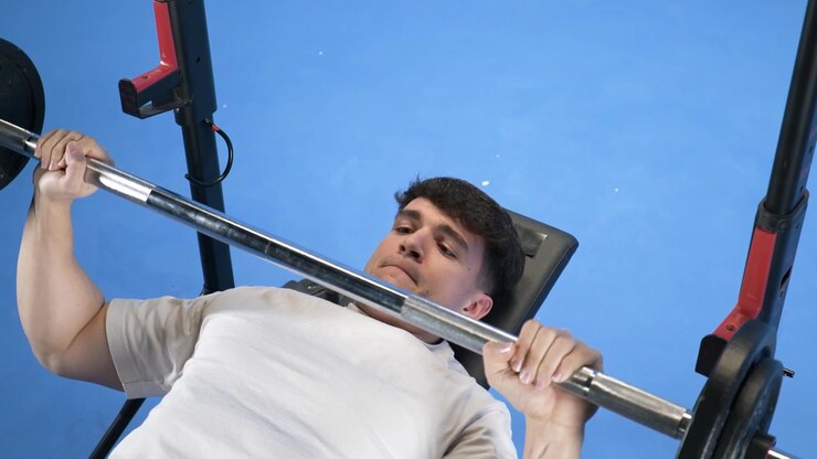 Young Man Performing Bench Press Exercise in Gym