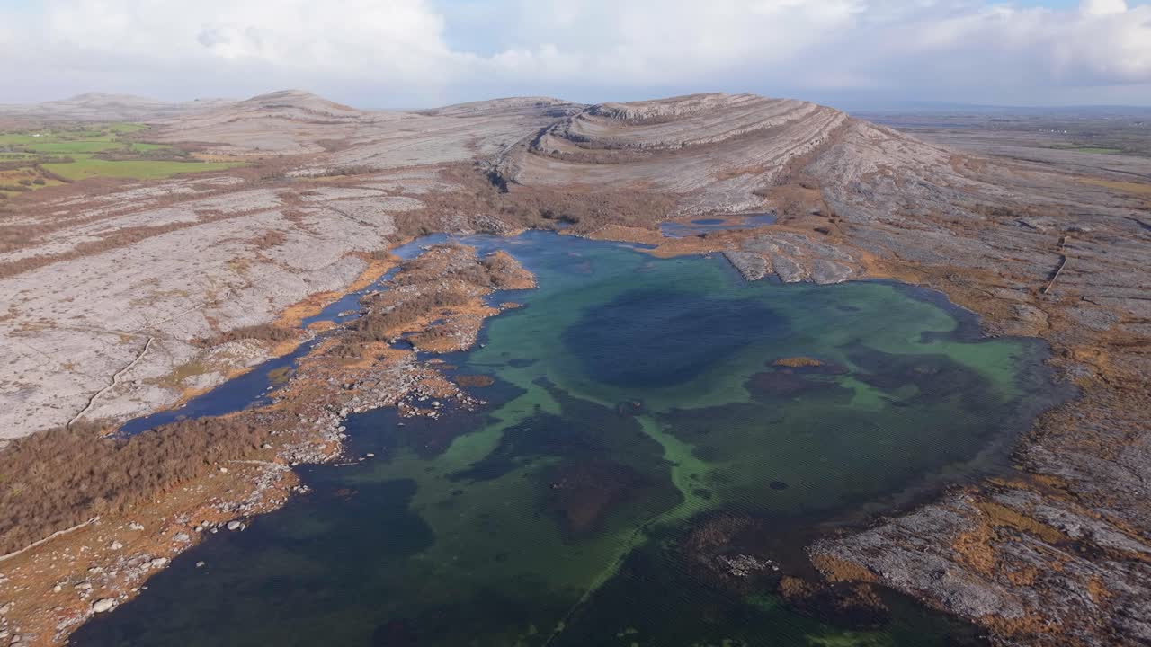 The burren, a rocky karst landscape with a vibrant green lake in ireland, aerial view
