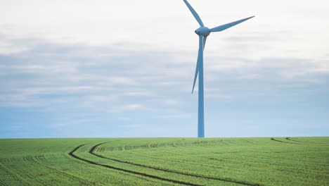 A-slowly-rotating-gigantic-wind-turbine-towers-in-the-green-farm-field