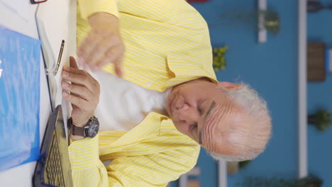 Vertical-video-of-Home-office-worker-old-man-getting-depressed.