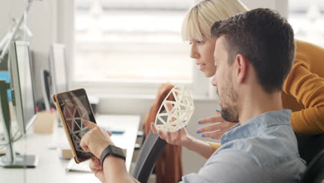 mujer de negocios que muestra un objeto impreso en 3d en una reunión de equipo de negocios creativos en una oficina de inicio neutral de género líder del equipo que señala a la pantalla discutiendo la tecnología de impresión en 3d