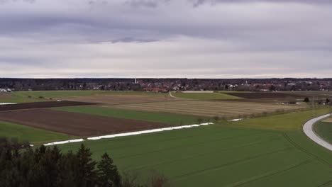 Antena-De-Un-Paisaje-Rural-Con-La-última-Nieve-Y-Un-Pueblo-De-Fondo