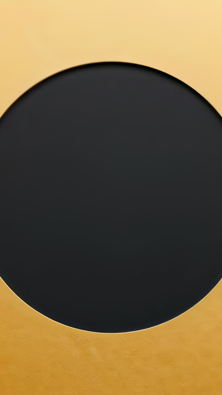Vertical video: Zooming camera revealing textured black panel in studio to highlight warm gold rim