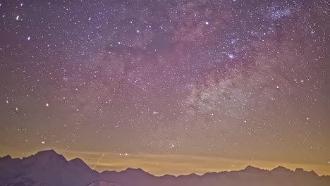 time lapse shot of moving stars at night sky with flying meteors above mountain range silhouette - wide shot