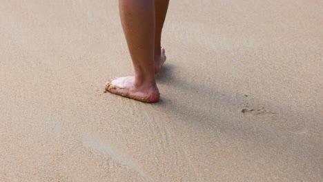 feet walking on sand, waves approaching gently