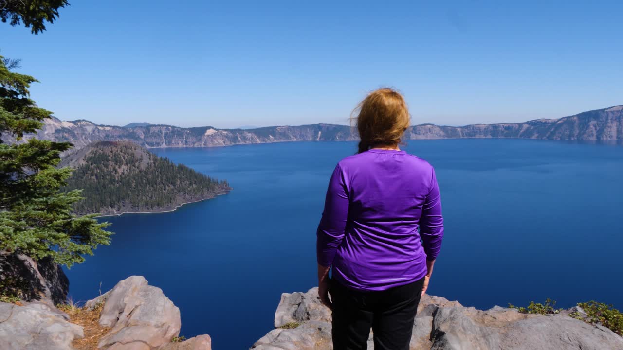 un turista mira la isla del mago desde el pase de descubrimiento en el parque nacional del lago del cráter