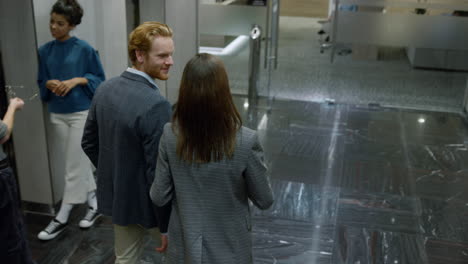 businessman and businesswoman talking in lift car. colleagues exiting elevator