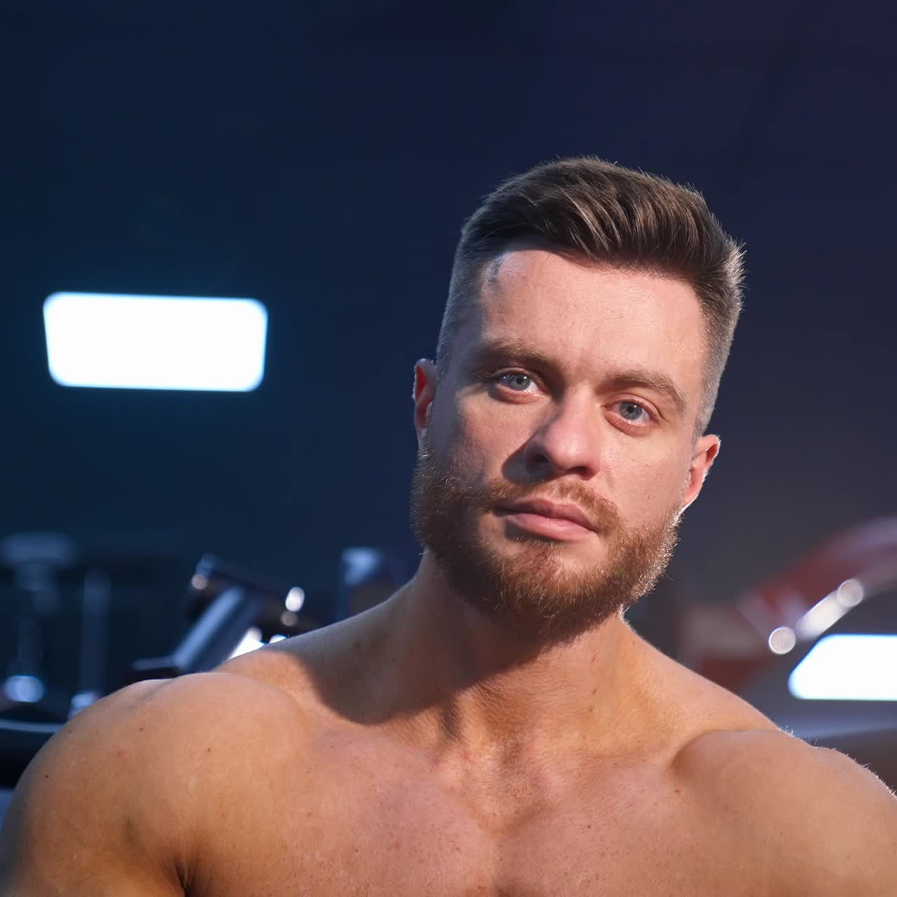 Athlete with strong body posing on gym background. Perfect man`s body. Slow motion