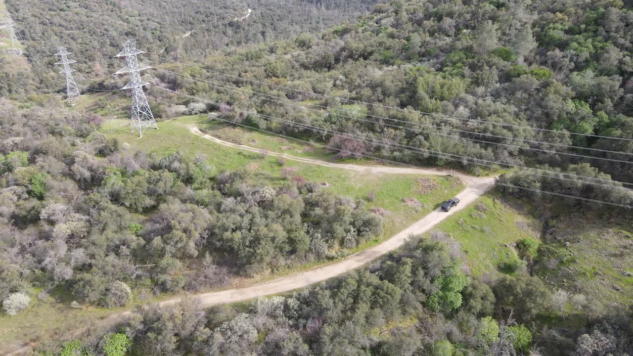 camioneta negra conduciendo bajo líneas eléctricas en un camino de tierra en las montañas