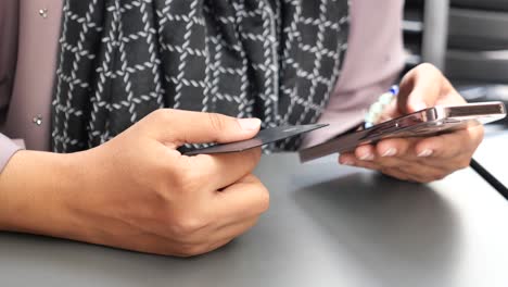 woman using a credit card to make a purchase on her phone