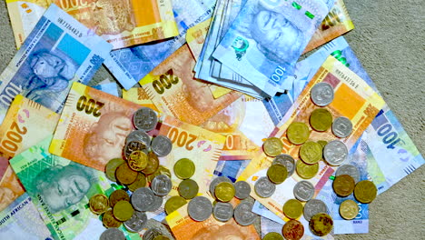 overhead twisting view of south african rand cash banknotes and coins