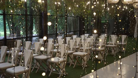 ceremony chairs aligned near glass wall under twinkling lights in intimate garden setting