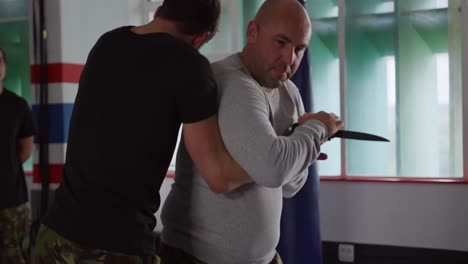 caucasian man learning self defense from trainer in gym