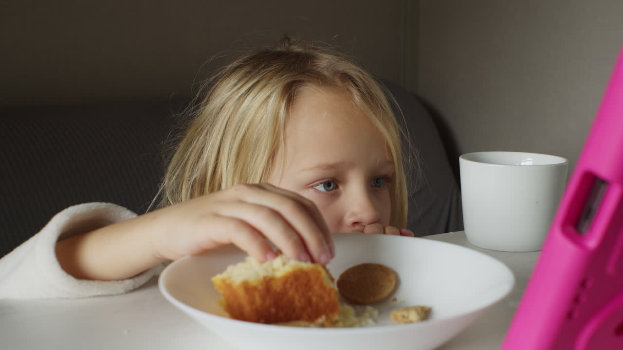 Child eating breakfast and watching tablet