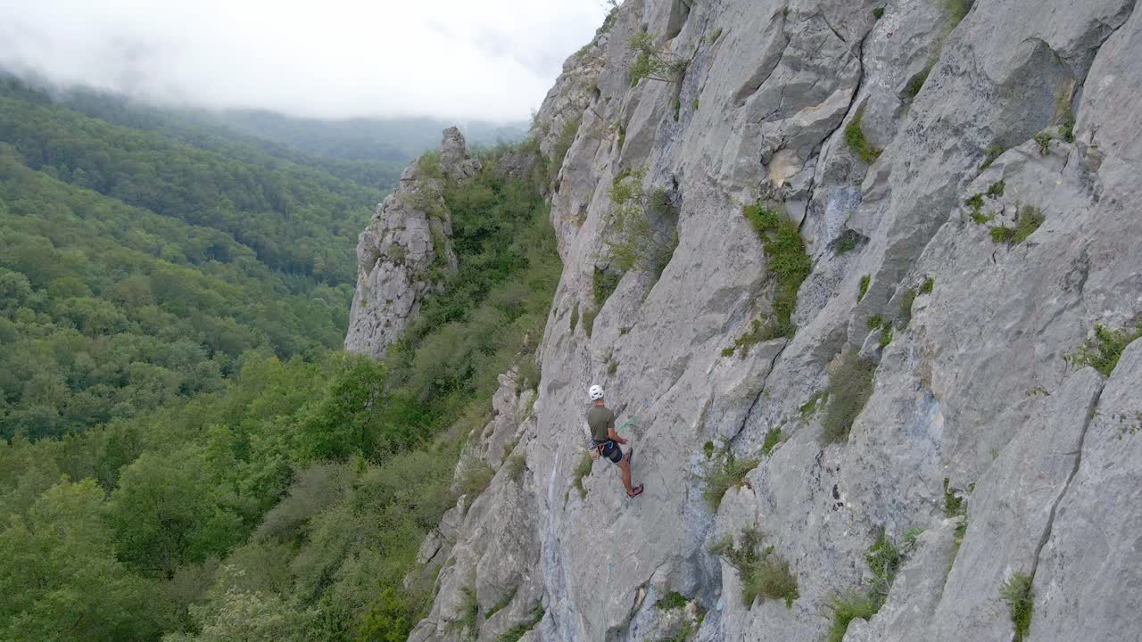 Top-down drone footage of a man stopped and using chalk while lead climbing in the Pyrenees moutains at Tarascon sur Ari&egrave;ge