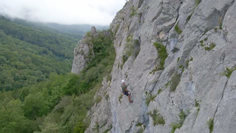 top-down drone footage of a man stopped and using chalk while lead climbing in the pyrenees moutains at tarascon sur ariège