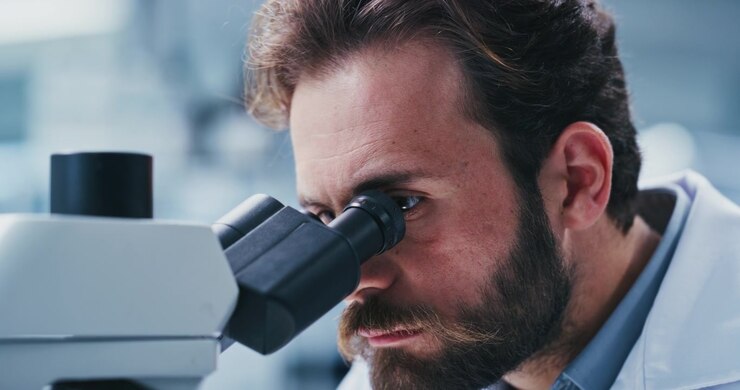 Male Scientist Looking Through Microscope in Laboratory