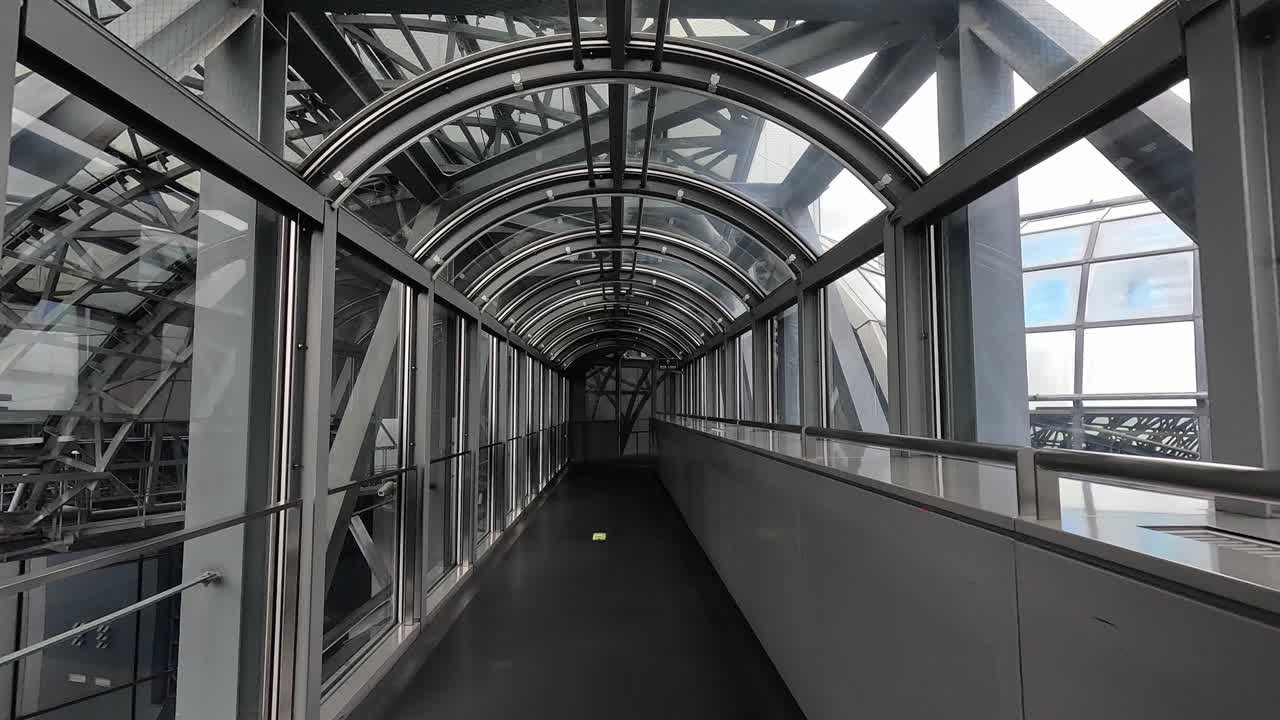 A sleek glass walkway tunnel inside Kyoto Station, Japan, showcasing futuristic architectural design.