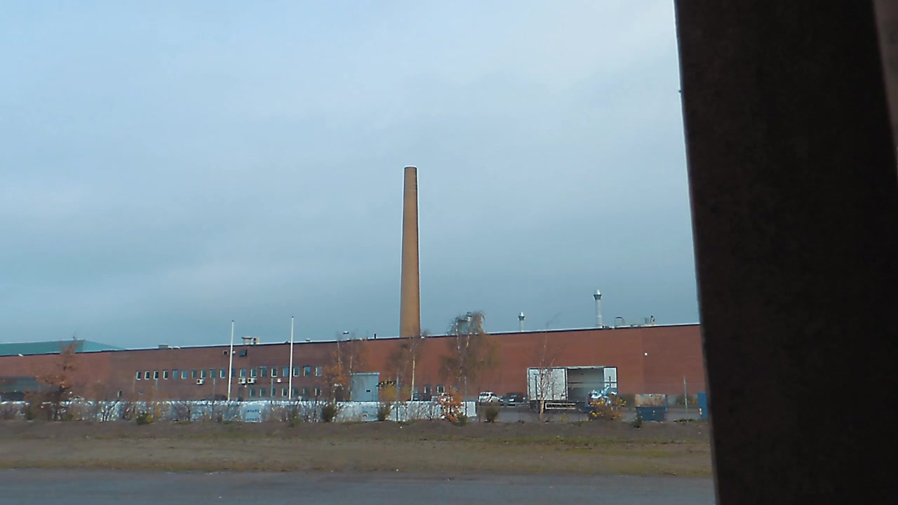 Toma deslizante desde detrás de una barra de hierro para enfocar una fábrica con una chimenea muy alta