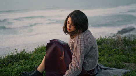 lonely girl sitting blanket with book enjoying sea view at dusk. woman relaxing.